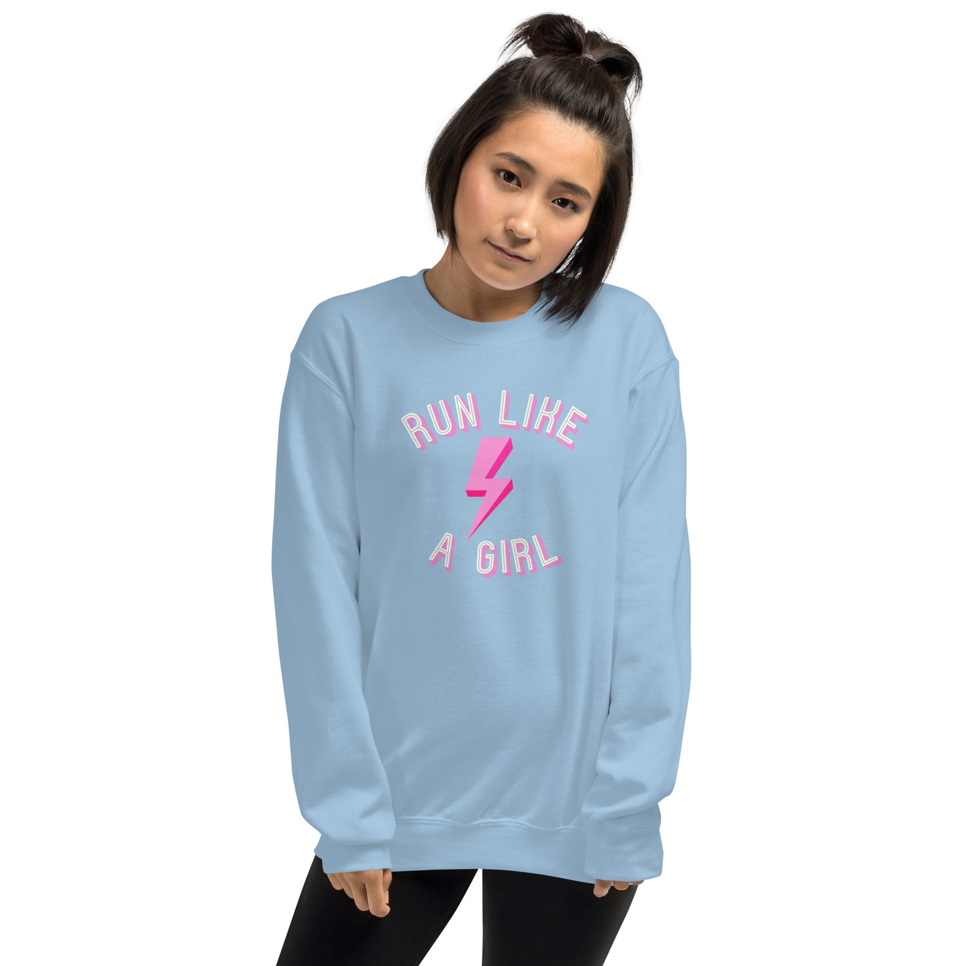 woman wearing a light blue sweatshirt with the words 'run like a girl' in a blue and pink font, wrapped around a pink lightening bolt