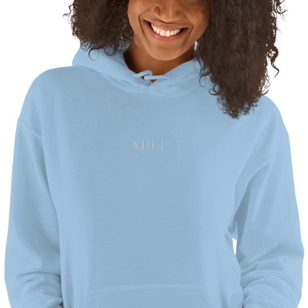 woman wearing a light blue unisex hoodie with XIII.I 13.1 half marathon in roman numerals embroidered in white writing